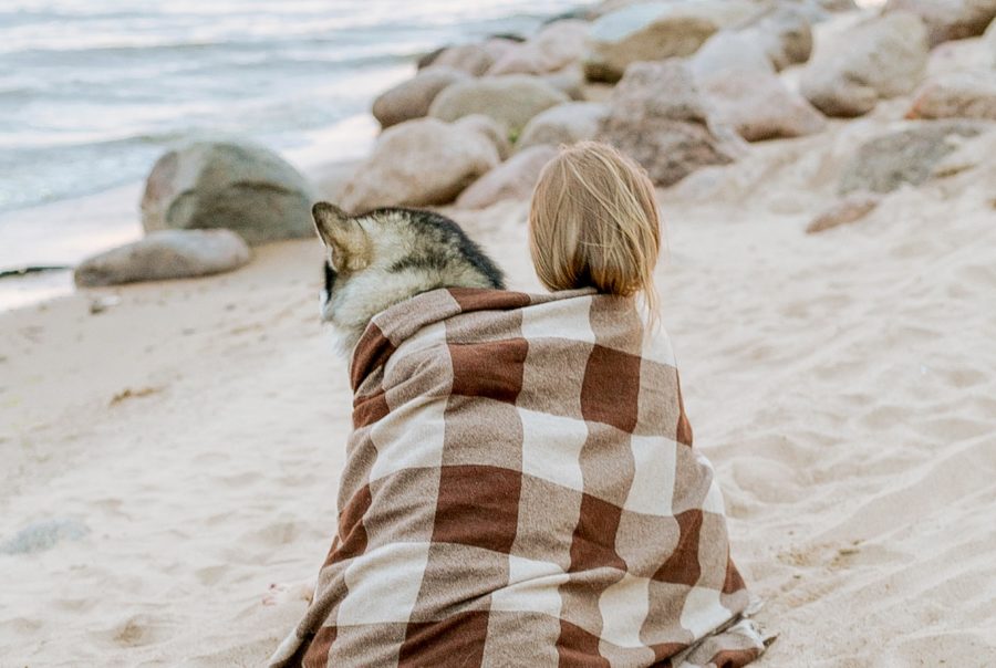 Woman in White and Brown Scarf Sitting on Beach with Dog