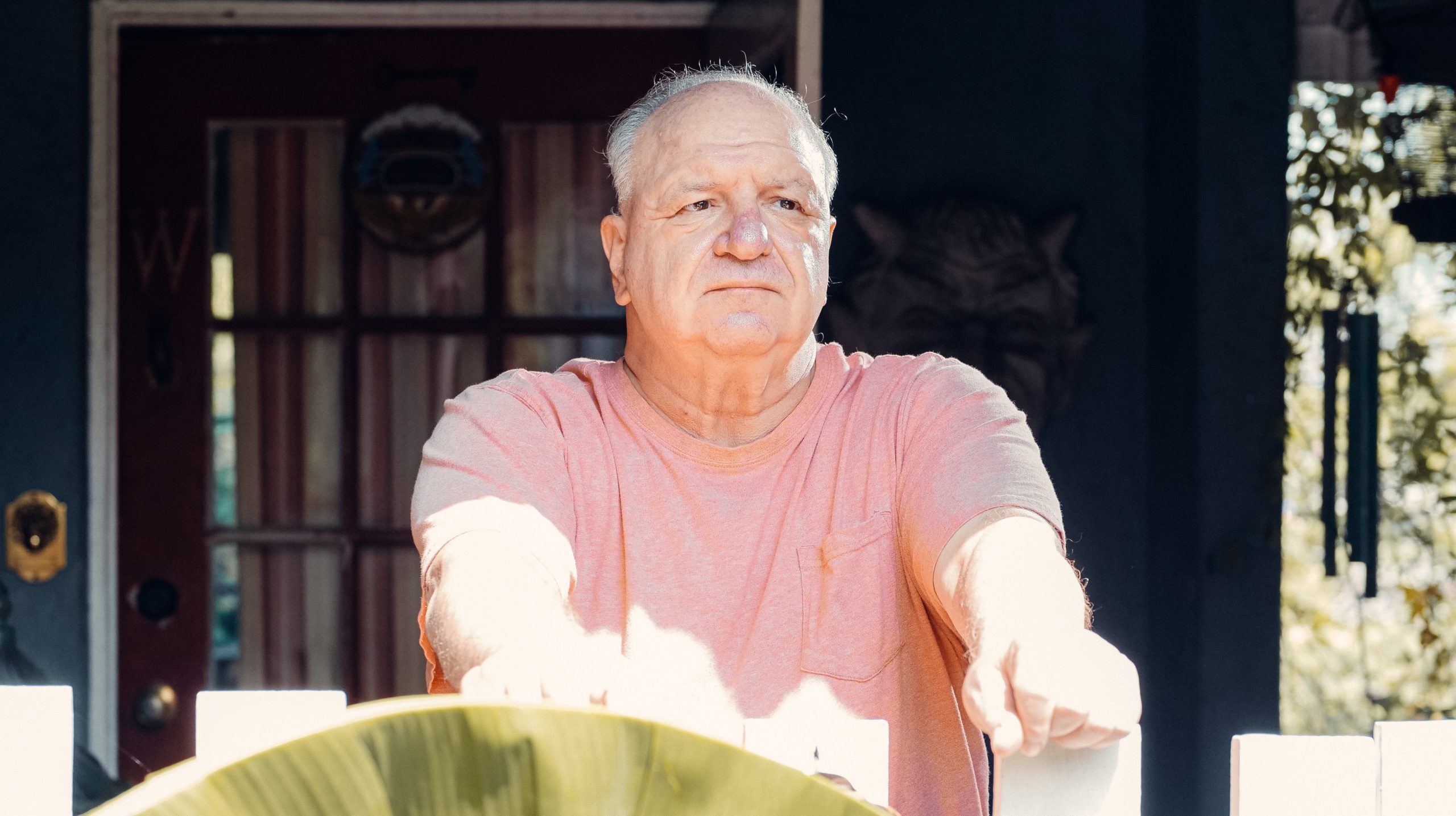 An Elderly Man with His Hands on a Wooden Fence