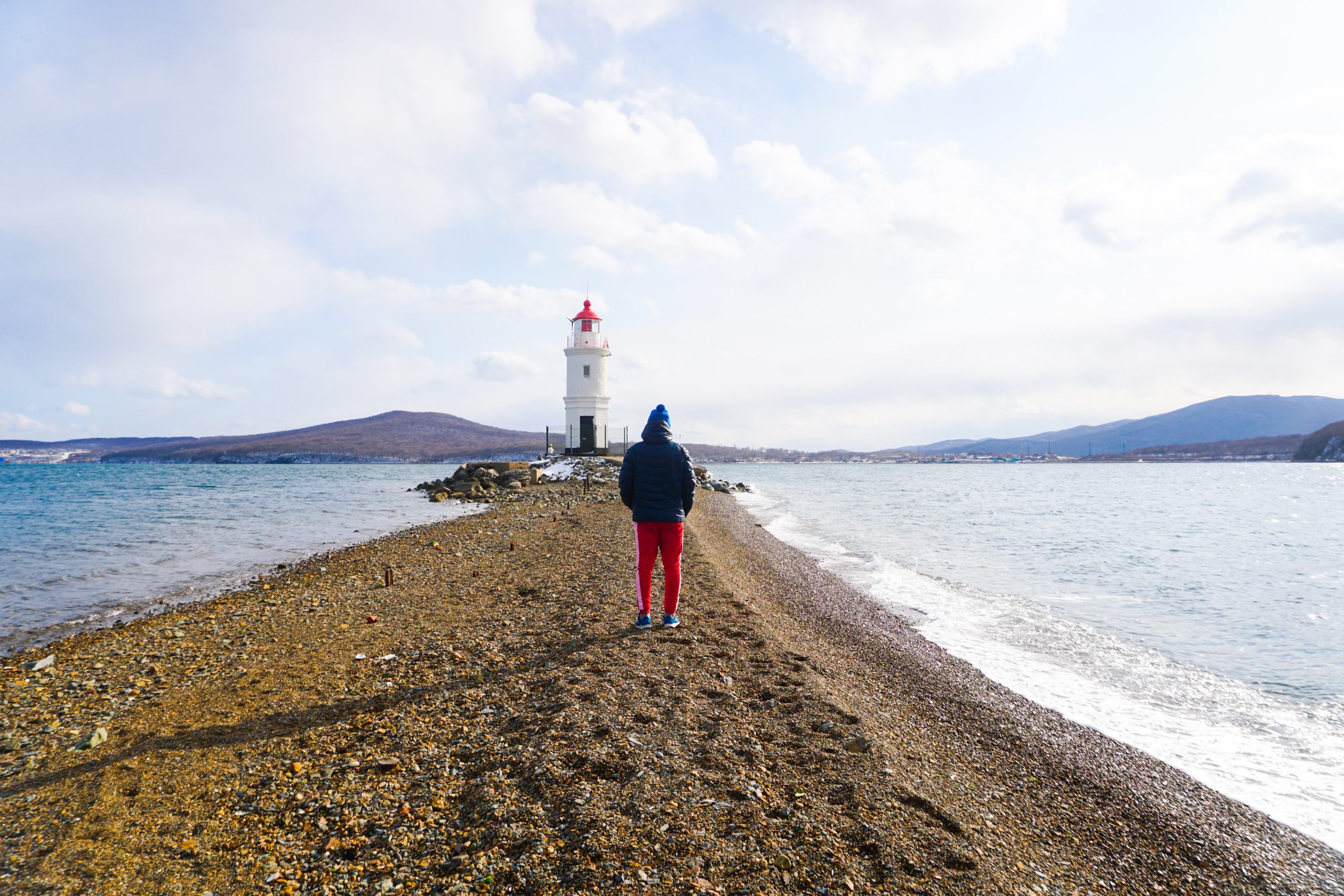 man walking towards lighthouse