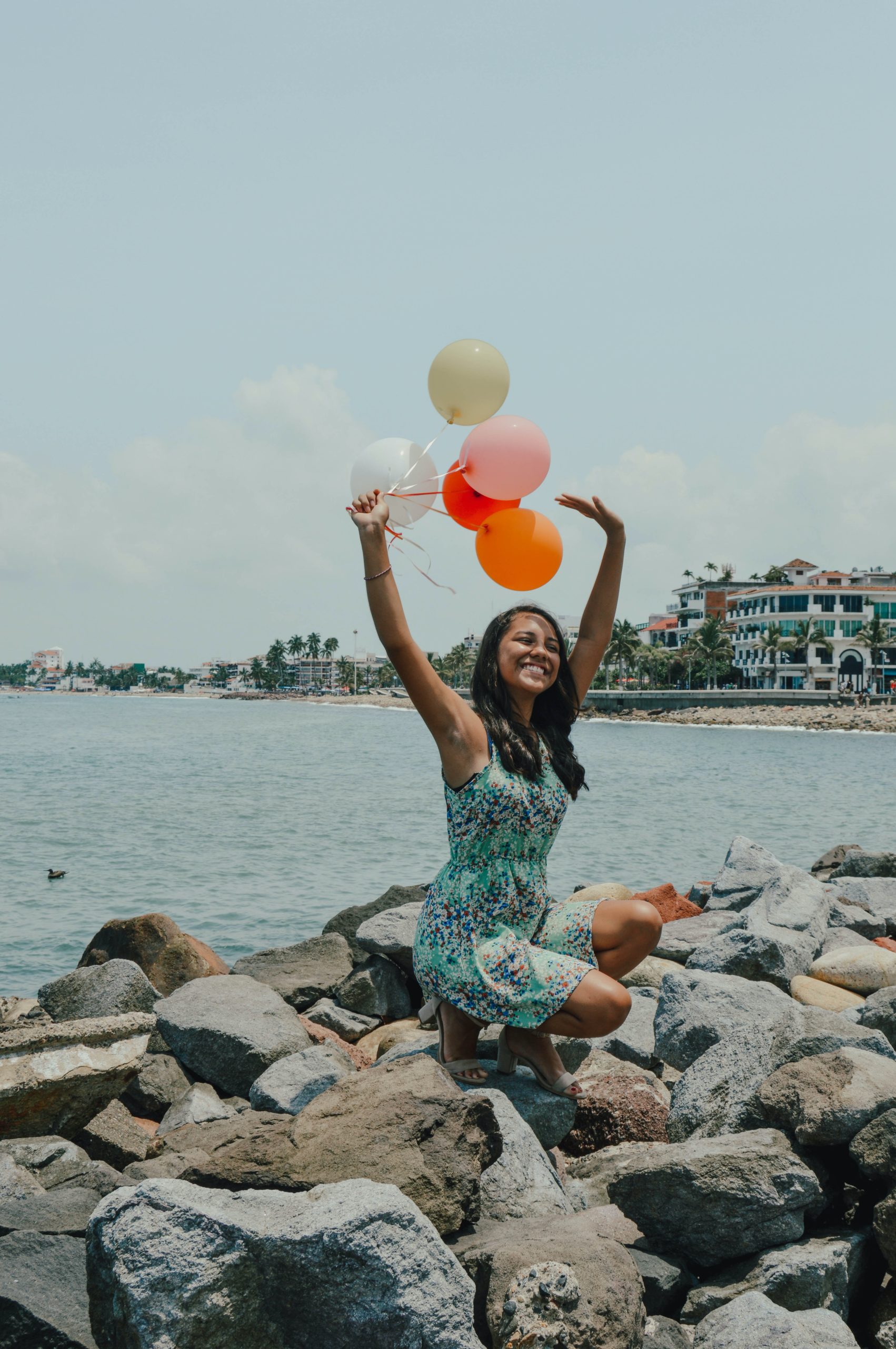 Woman with balloons near ocean